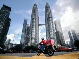 um entregador de comida em frente às torres petronas foto