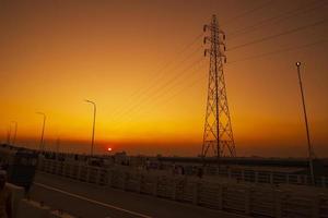 belo pôr do sol colorido com paisagem de pilão elétrico de alta tensão foto