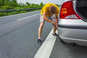 homem troca pneus de carro na estrada na alemanha. foto