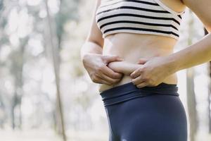 linda mulher gorda com fita métrica ela usa a mão para espremer o excesso de gordura que está isolado em um fundo branco. ela quer perder peso, o conceito de cirurgia e quebrar a gordura sob o foto