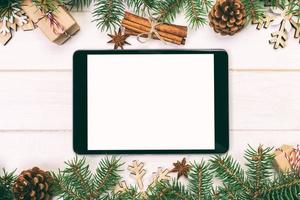 tablet digital simulado com decorações rústicas de fundo de madeira de natal para apresentação de aplicativos. vista superior com espaço de cópia. tonificado foto