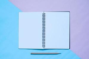 vista superior do caderno e lápis em fundo de cor pastel azul e pinl foto