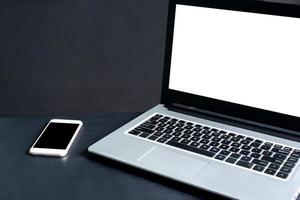 laptop, smartphone, na mesa de madeira preta com fundo preto foto