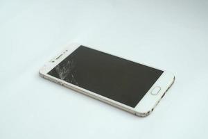 smartphone com tela quebrada em um fundo branco foto