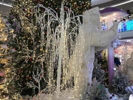 decorações de Natal. um urso polar alto fica ao lado de uma árvore de natal artificial. véspera de Natal. decoração do centro comercial. lindo e estiloso ano novo foto