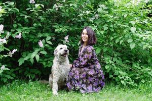 retrato de mulher jovem e bonita com cão pastor do sul da Rússia em um fundo de parque de verão com arbustos lilás florescendo. foto