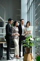 um grupo de jovens empresários asiáticos está sendo realizada uma reunião para revisar as informações de investimento em ações em uma sala de reuniões com luz natural foto