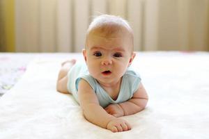 linda menina rastejando em uma cama em casa. foto