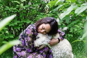 retrato de mulher jovem e bonita com cão pastor do sul da Rússia em um fundo de arbustos lilás florescendo. foto