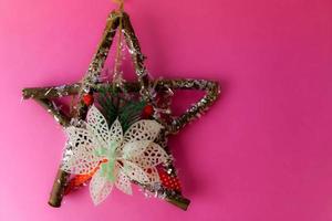 grande decorativa linda estrela de natal de madeira, uma coroa de advento self-made de ramos de abeto e varas sobre o fundo alegre rosa roxo feliz ano novo festivo. decorações de férias foto