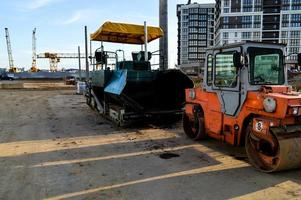 máquina para criar uma superfície melhorada na estrada ao lado do rolo de asfalto. dispositivos para a construção da rodovia. estradas suaves e bonitas e seguras no centro da cidade foto