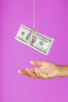 dinheiro em uma corda acima da palma da mão em um fundo rosa. foto