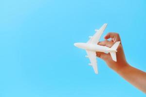 um avião de brinquedo branco na mão de uma criança contra um céu azul. foto