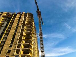 construção de um novo edifício. um guindaste transporta pesadas lajes de concreto para construir pisos. casas sem janelas, com curvas inusitadas. nova tecnologia para a comodidade dos moradores foto