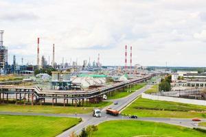 paisagem industrial. vista panorâmica dos tubos tecnológicos. configurações da planta. dos tubos químicos vermelho-branco vem fumaça. edifícios de produção. contra o fundo do céu e grama brilhante foto