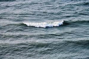 águas do mar azul profundo espirrando com ondas espumosas, superfície da água do oceano ondulado azul escuro, mar tempestuoso foto