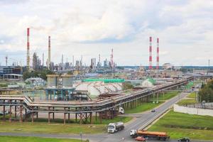 paisagem industrial. vista panorâmica dos tubos tecnológicos. configurações da planta. dos tubos químicos vermelho-branco vem fumaça. edifícios de produção. contra o fundo do céu e grama brilhante foto