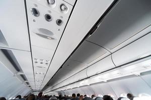 painel de controle do ar condicionado do avião sobre os assentos. ar abafado na cabine do avião com pessoas. nova companhia aérea de baixo custo foto