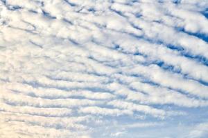 lindo céu azul com nuvens de altocumulus undulatus brancas incomuns, formação de nuvens extraordinária foto