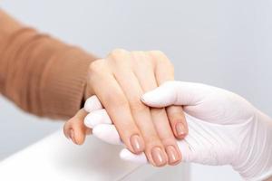 mão segurando os dedos femininos com manicure bege foto