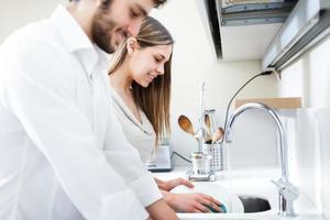 jovem casal lavando pratos foto