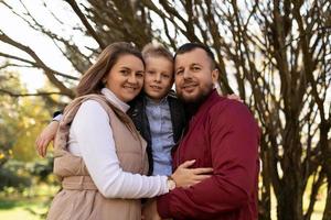 retrato de mãe feliz pai e filho entre eles contra o pano de fundo de um parque de outono foto