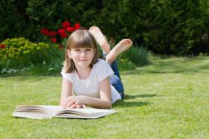 menina lendo um livro em um jardim foto