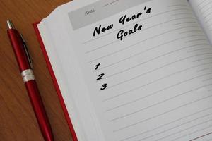 bloco de notas com uma caneta em uma mesa de madeira. vista de cima. o conceito de metas para o novo ano. foto