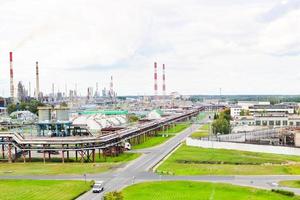 paisagem industrial. vista panorâmica dos tubos tecnológicos. configurações da planta. dos tubos químicos vermelho-branco vem fumaça. edifícios de produção. contra o fundo do céu e grama brilhante foto