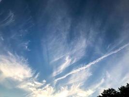 céu azul com nuvens brancas. fenômeno natural, belas nuvens. à distância, traços de branco de um avião voando são visíveis. nuvens em aquarela, camada de ozônio. céu de verão foto