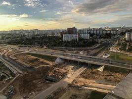 tiro do telhado da casa, fotografia aérea. construção de um entroncamento rodoviário. grande cruzamento asfalto-concreto. ponte no centro da cidade para carros que passam. contra foto