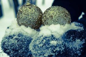 lindas bolas redondas amarelas e douradas elegantes festivas, decorações de natal para o ano novo, o natal está nas mãos em luvas pretas no contexto da neve branca no inverno foto