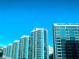 os topos das altas casas de vidro azul contra o céu azul pálido. efeito elegante brilhante incomum. cor quente dos edifícios. casas azuis e brancas de forma retangular, colunas altas foto