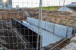 malha metálica densa e grossa no canteiro de obras. cercar canteiros de obras especialmente perigosos de visitantes. atrás da grade há uma vala de areia com armação de metal foto