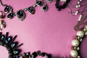 belas jóias brilhantes preciosas na moda conjunto de jóias glamourosas, colar, brincos, anéis, correntes, broches com pérolas e diamantes em um fundo rosa roxo. configuração plana, vista superior, local de cópia foto
