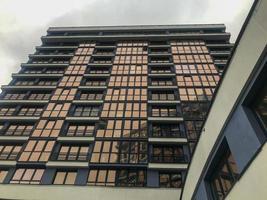 edifício residencial, alto, com janelas foscas no centro da cidade. um arranha-céu de vidro azul e branco com transição para outro edifício. janelas foscas com um efeito marrom incomum. foto