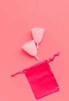 copo menstrual rosa na cor de fundo, produtos do período de higiene íntima feminina, vista superior foto