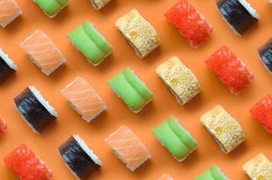 diferentes tipos de rolos de sushi asiáticos em fundo laranja. minimalismo vista superior plana padrão leigo com comida japonesa foto