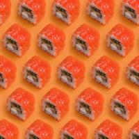 Rolos de sushi maki da Califórnia com caviar e masago em fundo laranja. minimalismo vista superior plana padrão leigo com comida japonesa foto