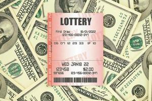 bilhete de loteria vermelho encontra-se em grande quantidade de notas de cem dólares. conceito de jogo de loteria ou vício em jogos de azar. fechar-se foto