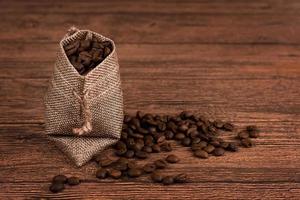 saco de embalagem de folha de café preto na vista superior da mesa de madeira. conceito de leigos plana de feijão derramado. espaço para texto. foto