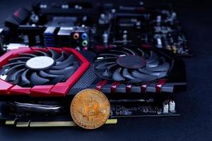 conceito de mineração de criptomoeda com moedas de bitcoin douradas ao lado de um fundo preto de placa de vídeo com desempenho de computador foto