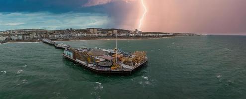 vista aérea do cais do palácio de brighton, com a beira-mar atrás. foto aérea da deslumbrante cidade de brighton e hove com gaivotas voando durante tempestade e relâmpagos.