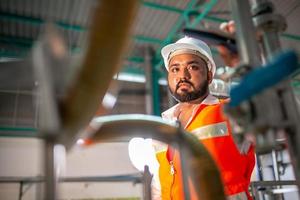 engenheiro técnico profissional com capacete de segurança trabalhando para manutenção de equipamentos de construção em fábrica industrial, trabalhador está verificando ou reparando a máquina. foto