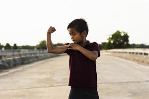 um menino mostrando os músculos do braço uma foto de um menino asiático.