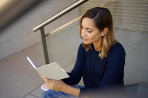 mulher de meia idade lendo com seu e-book em uma pausa para o café perto de seu escritório. foto