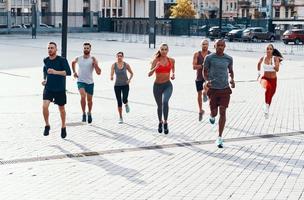 comprimento total de pessoas em roupas esportivas correndo enquanto se exercita na calçada ao ar livre foto