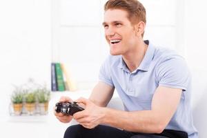 jogando seu videogame favorito. jovem feliz usando joystick enquanto joga videogame em casa foto