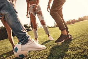 pronto para jogar. close-up de jovens em roupas casuais jogando futebol enquanto passam tempo ao ar livre foto