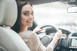 confiante e bonita. vista traseira de uma jovem atraente em roupas casuais, olhando por cima do ombro enquanto dirigia um carro foto